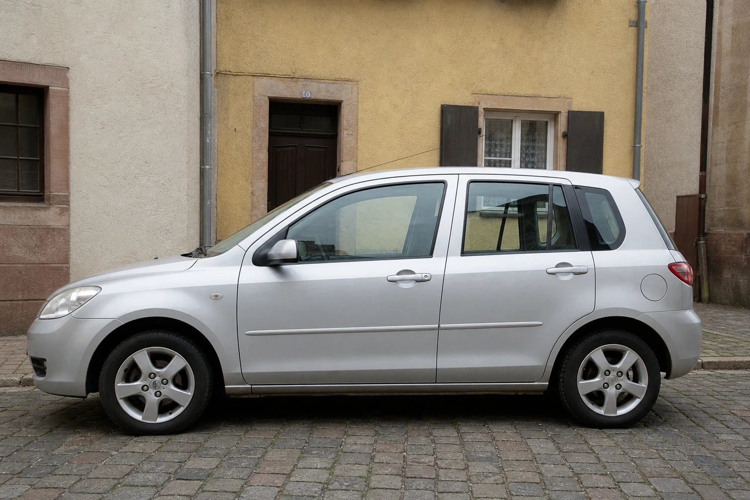 Seitenansicht (Fahrerseite) des Mazda 2 1. Gen als 3-, 5-Türer (mit KI erzeugt)
